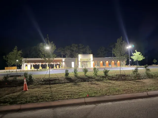 Wide night view of a commercial bank building with a lit drive-thru canopy, parking-lot pole lights and landscape lighting, Kinston NC